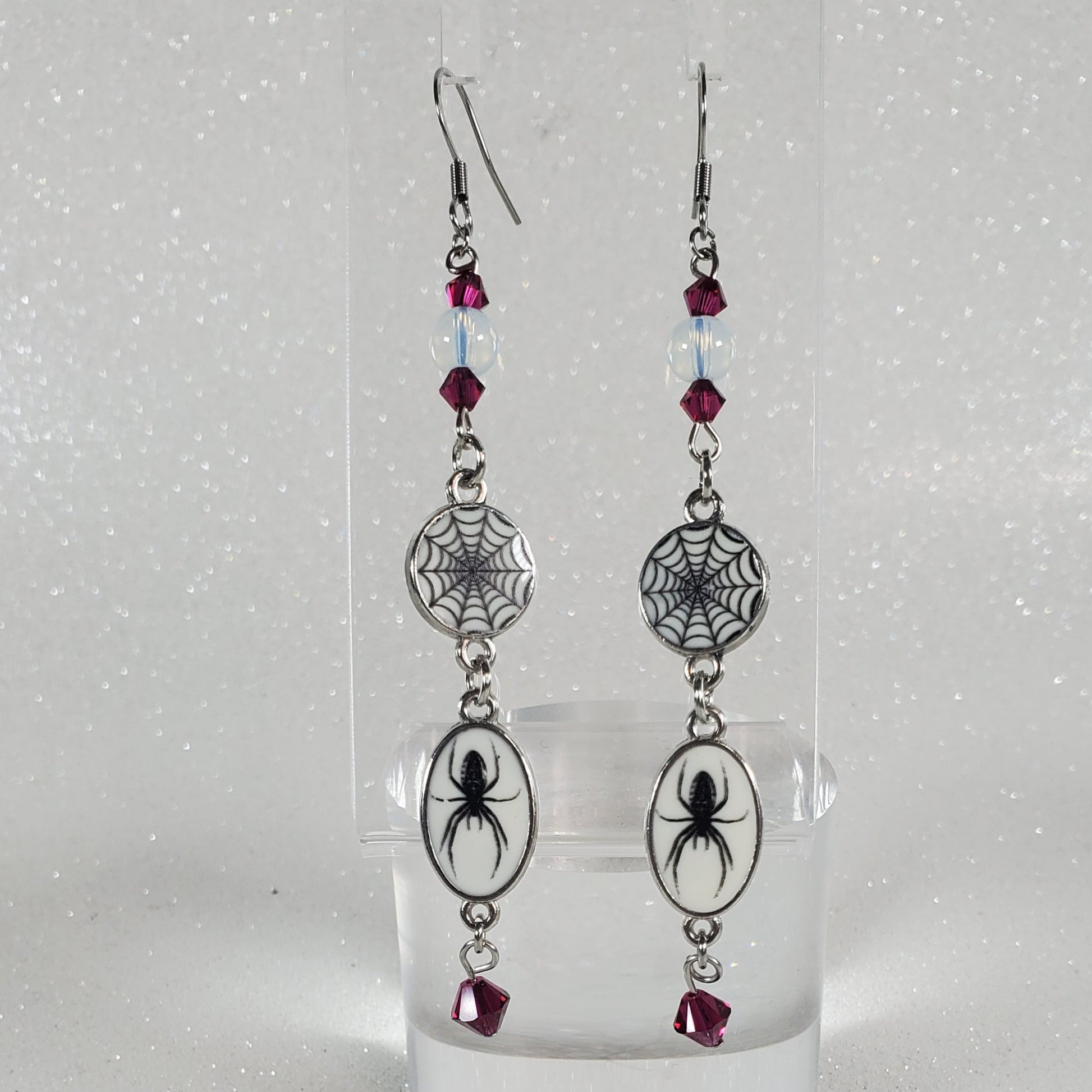 Pair of earrings with spider and web design on a clear background