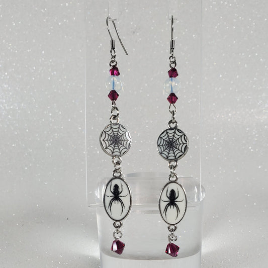 Pair of earrings with spider and web design on a clear background