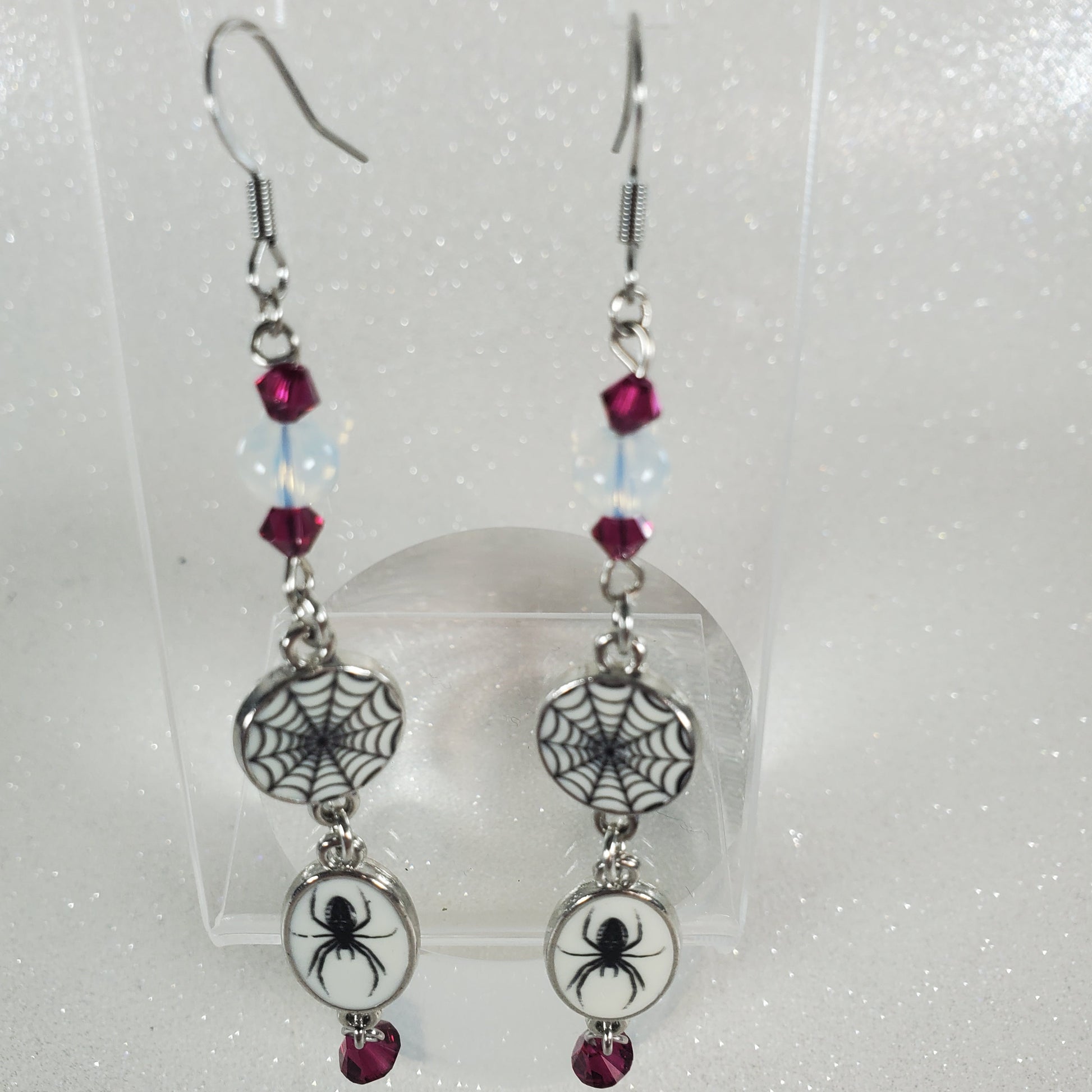 Pair of earrings with spider and web designs on a white background