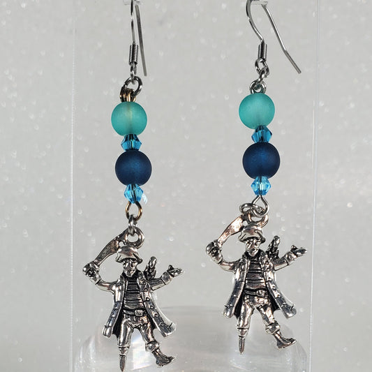 Pair of earrings with blue beads on a clear stand against a light gray background