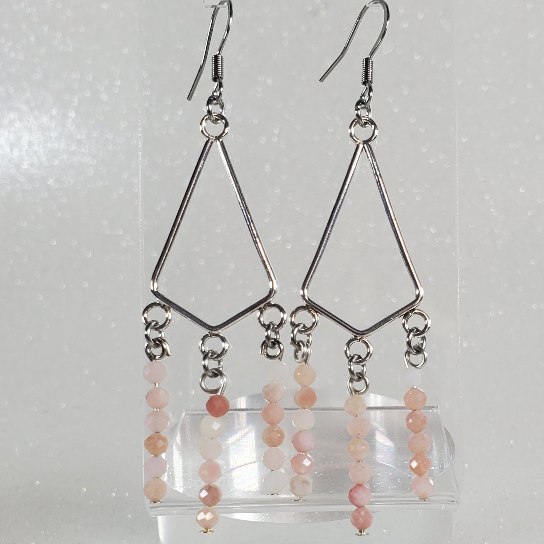 Set of earrings on a clear stand against a white background