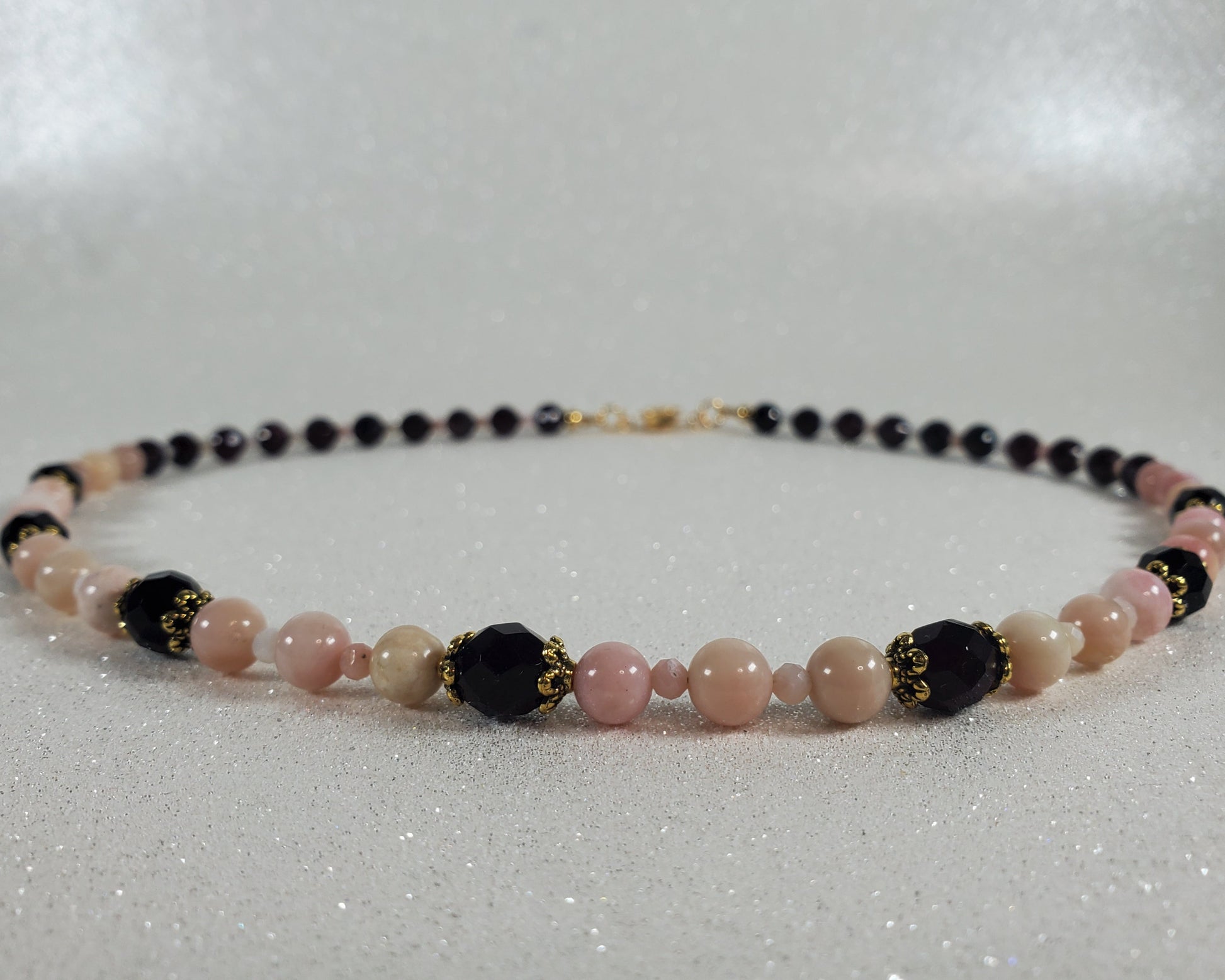 Beaded necklace with pink, red, and gold beads on a white background