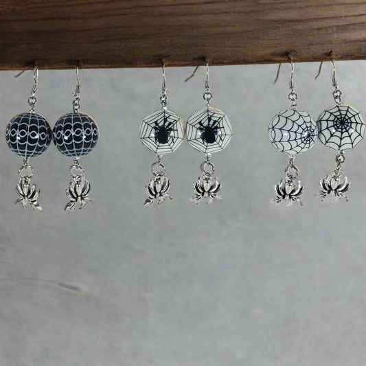 Pair of Halloween-themed earrings with spider webs and spiders on a white card.