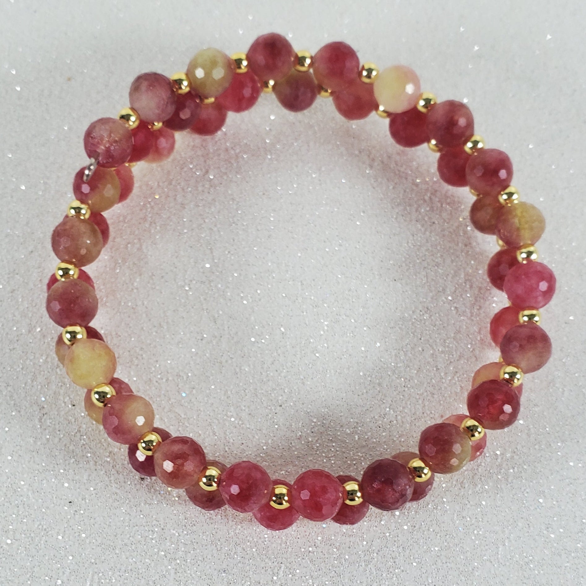 Beaded bracelet with red and gold beads on a light gray background