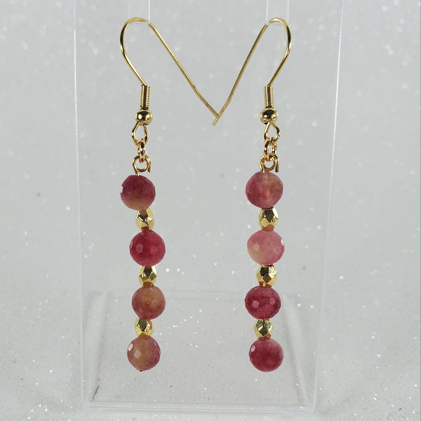 Pair of earrings with red beads and gold hooks on a clear background