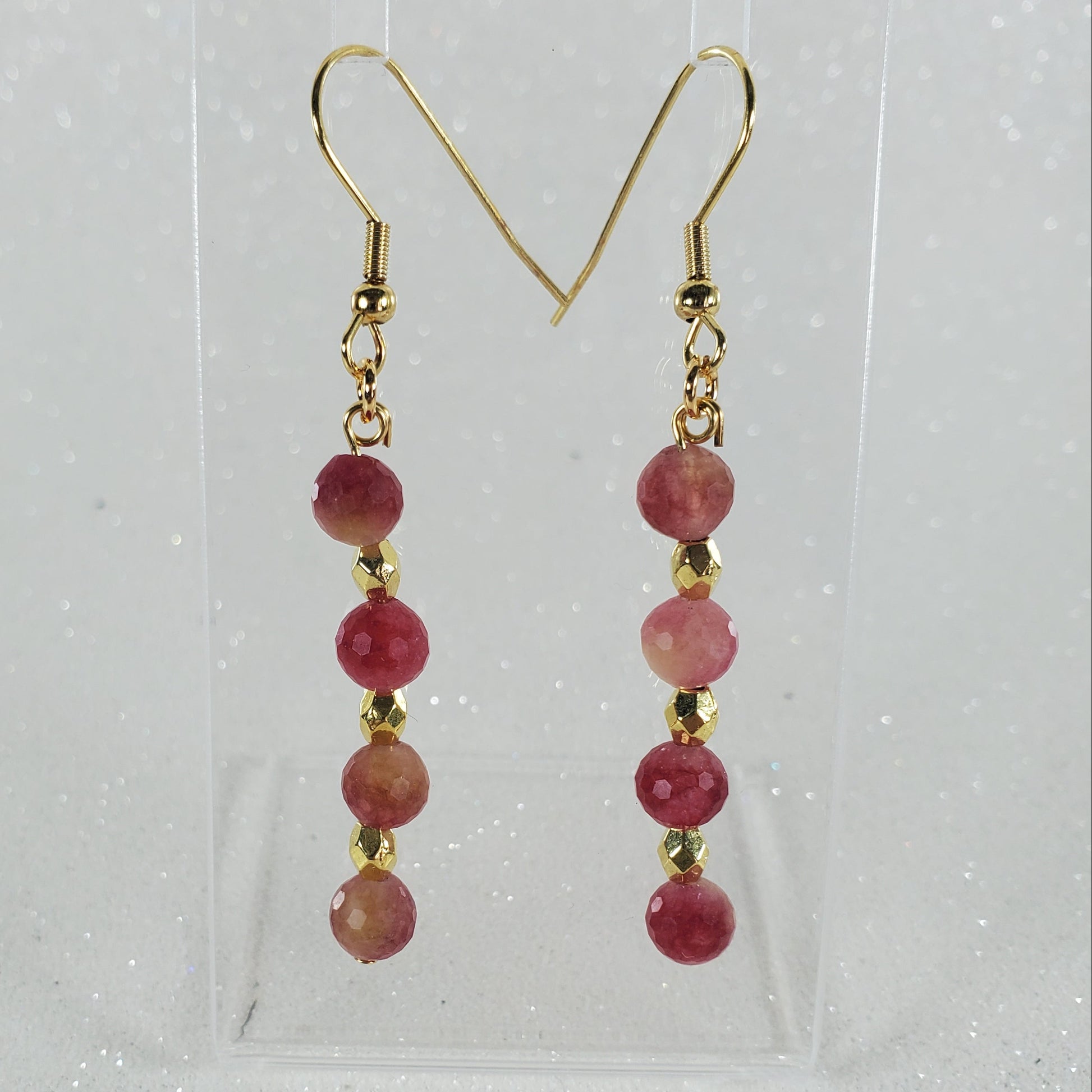 Pair of earrings with red beads and gold hooks on a clear background