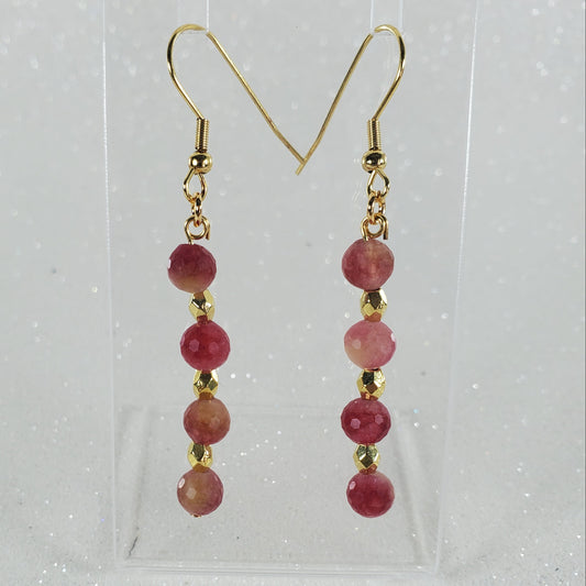 Pair of earrings with red beads and gold hooks on a clear background