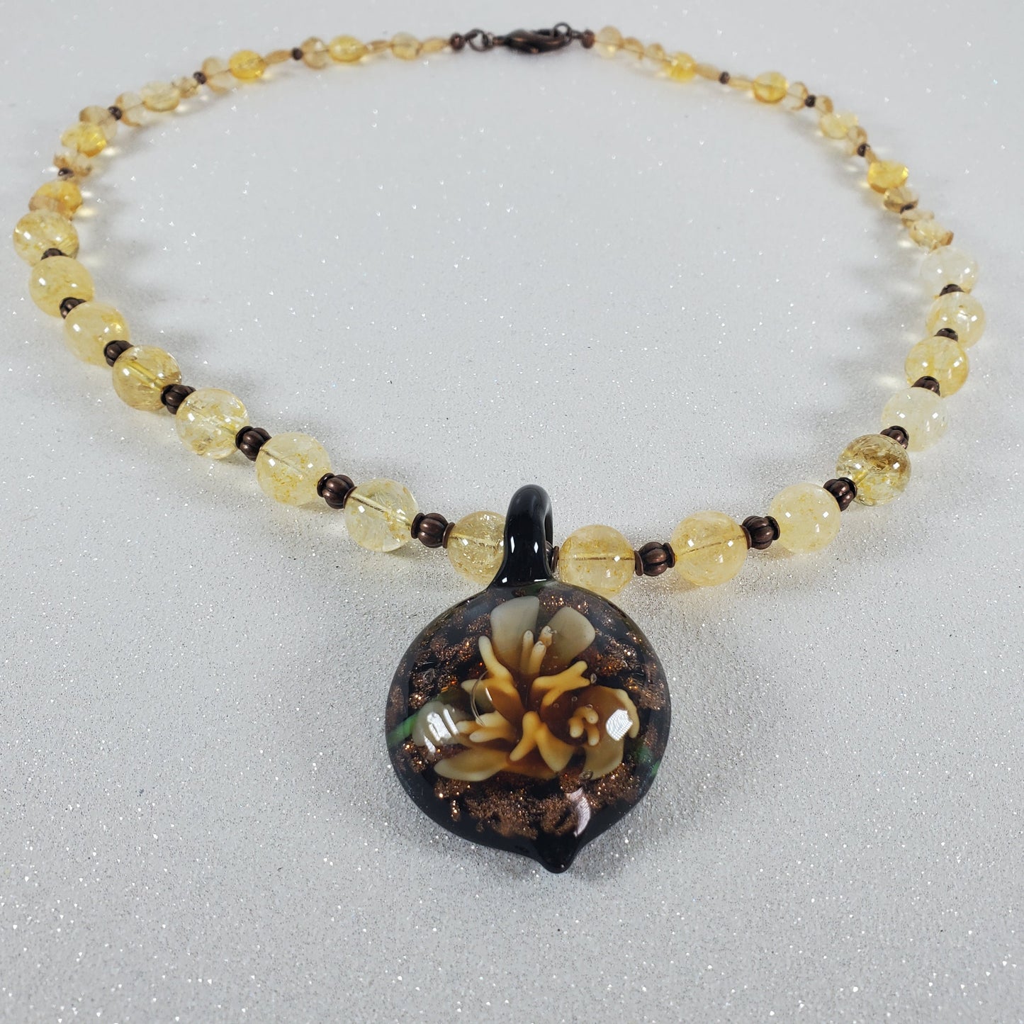Necklace with yellow beads and a dark pendant on a light gray background