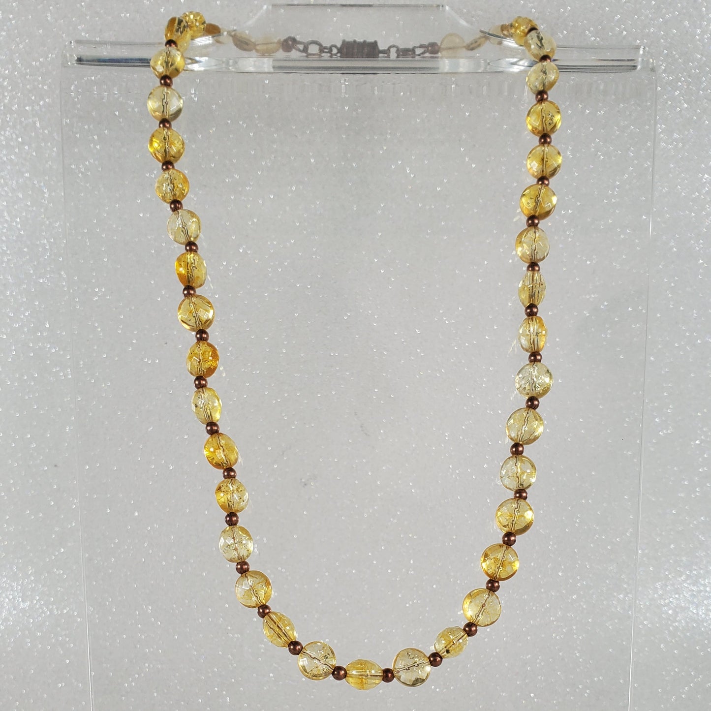 Beaded necklace on a clear stand against a white background