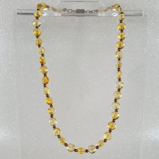 Beaded necklace on a clear stand against a white background