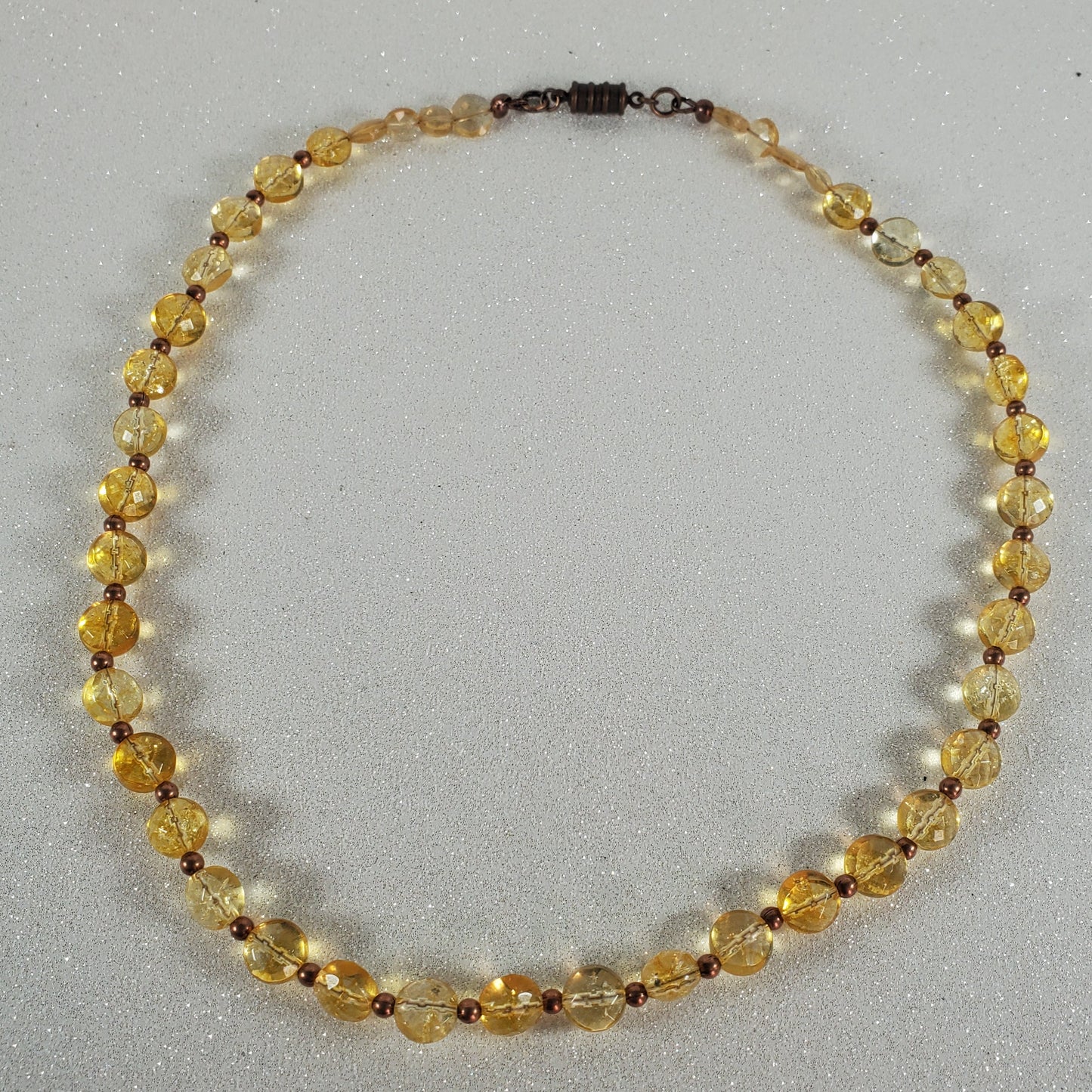 Beaded necklace with yellow and brown beads on a gray background
