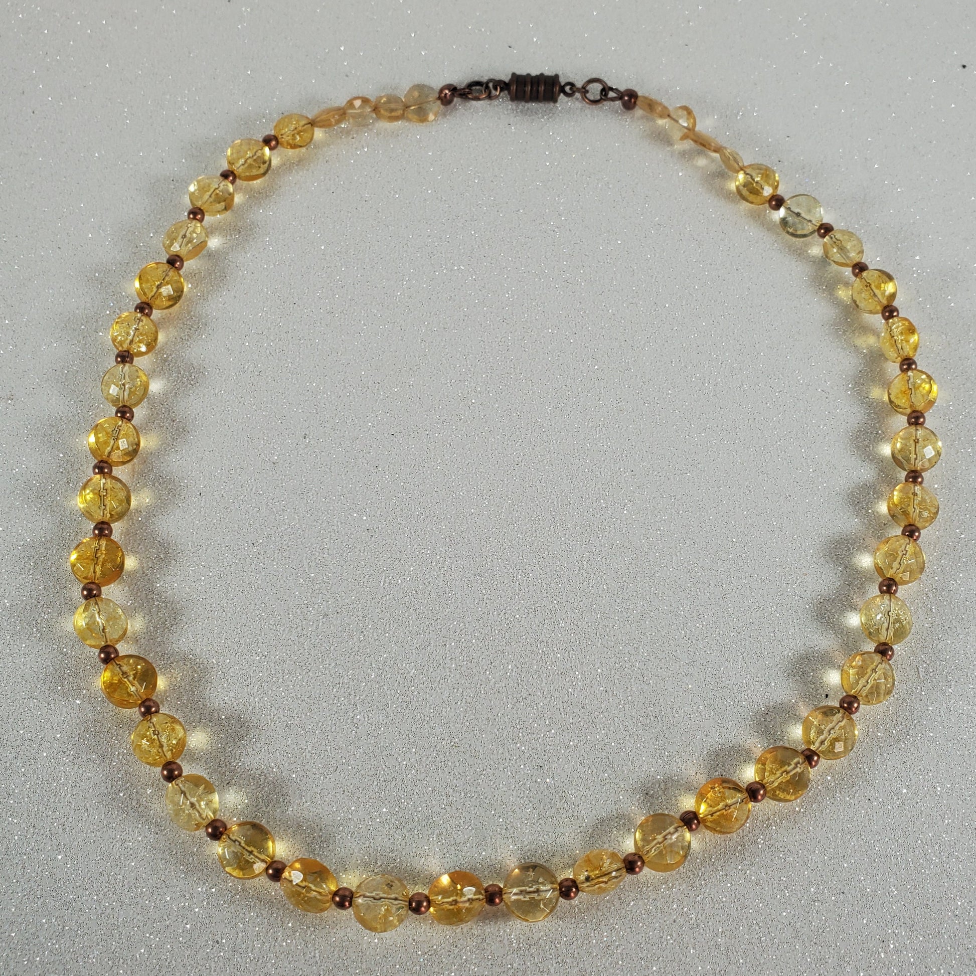 Beaded necklace with yellow and brown beads on a gray background