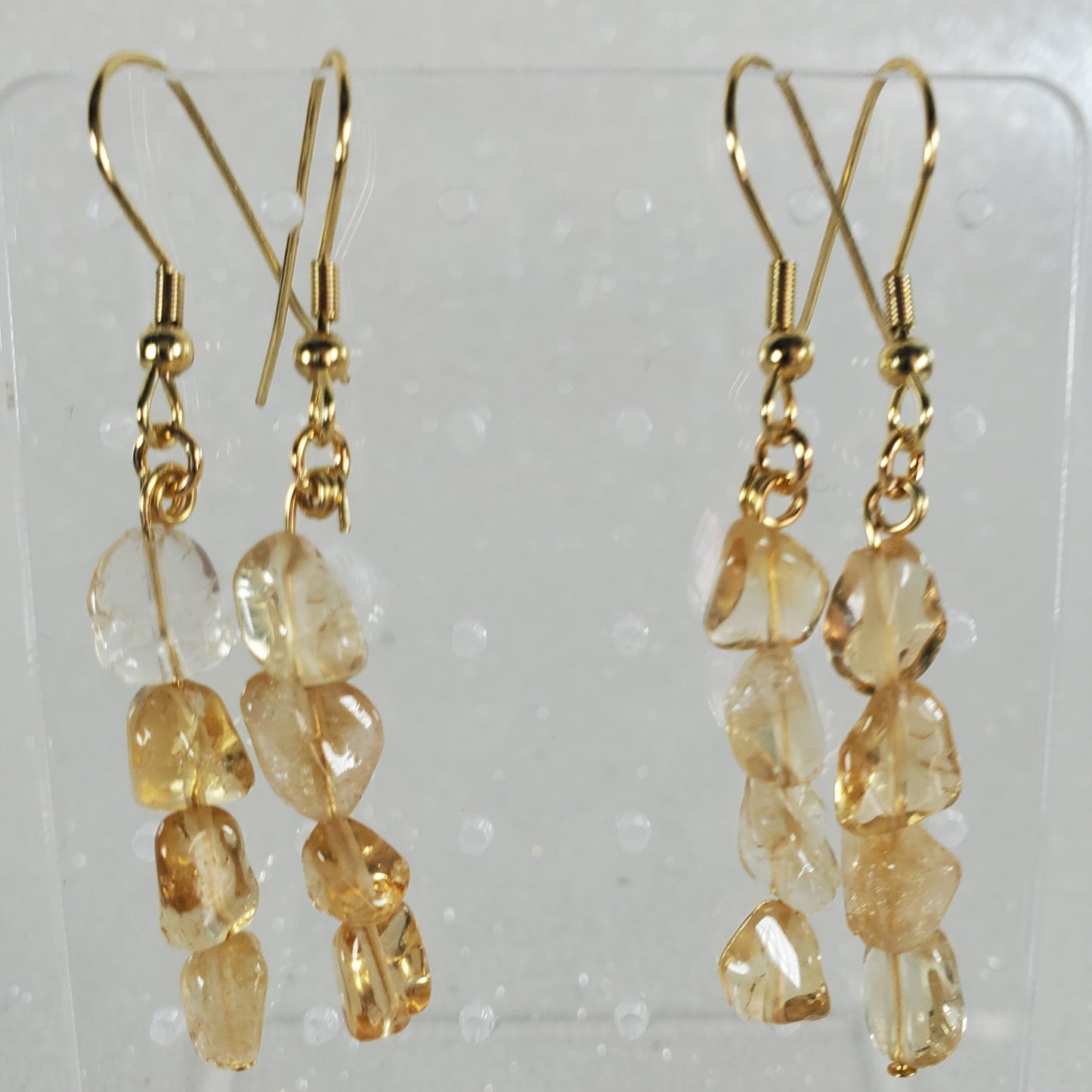 Pair of gold earrings with clear stones on a white background