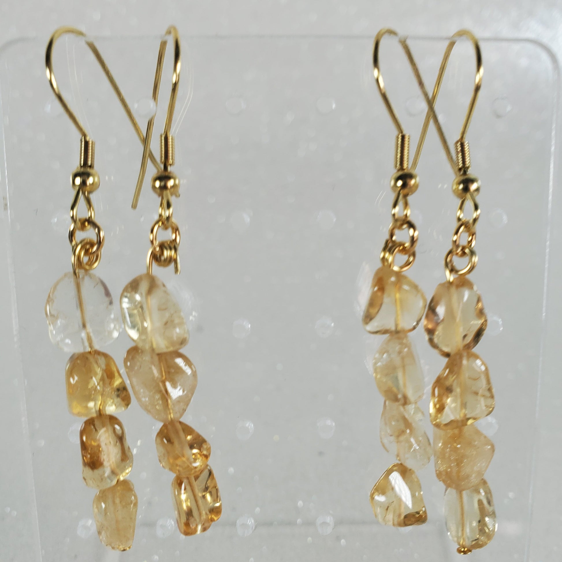 Pair of gold earrings with clear stones on a white background