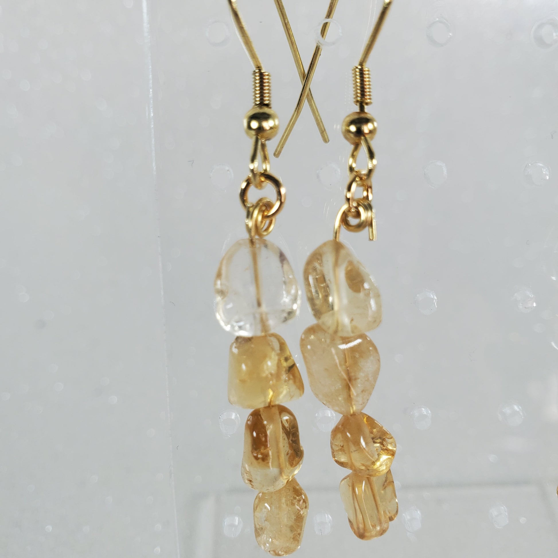 Gold earrings with clear and amber beads on a white background