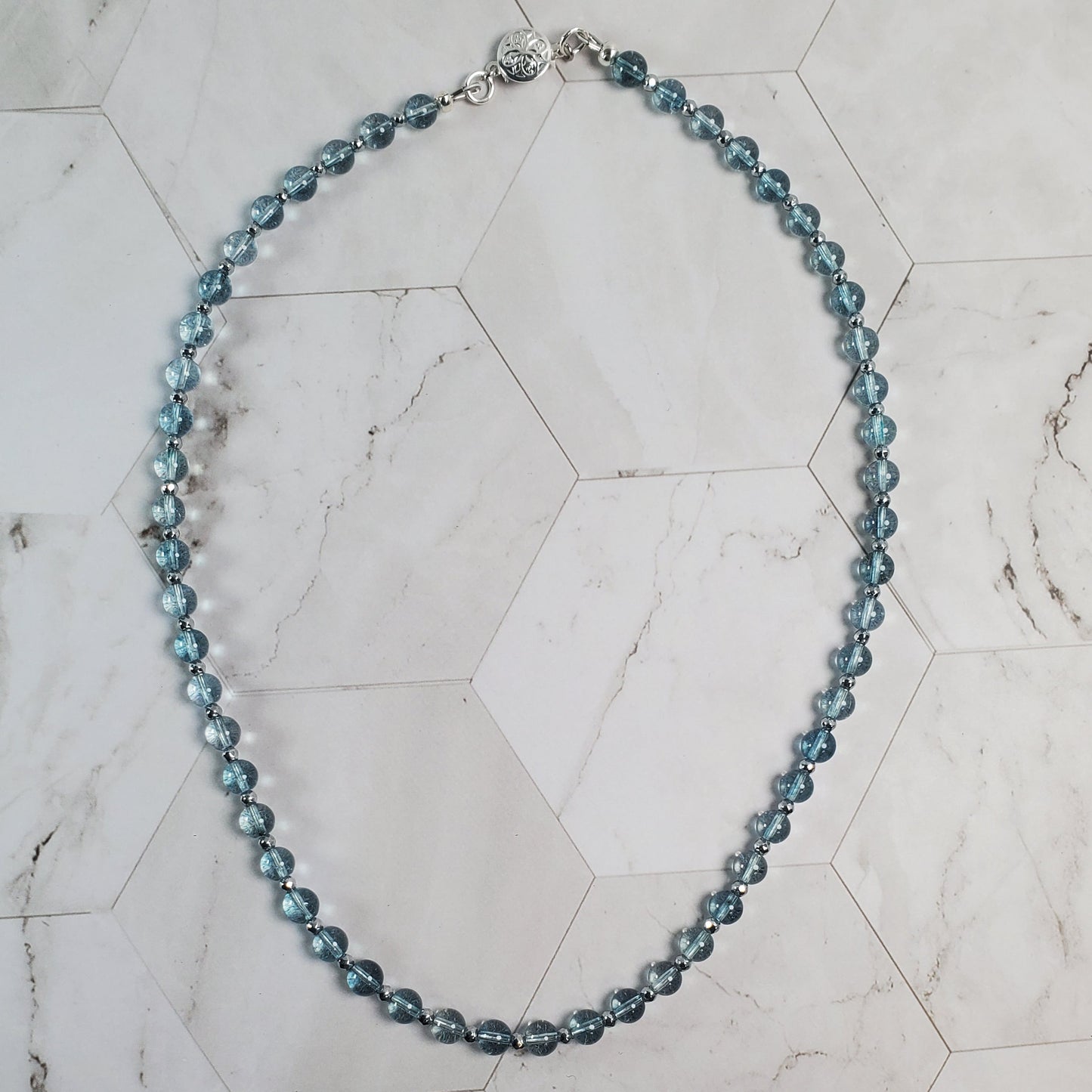 Blue beaded necklace on a marble surface