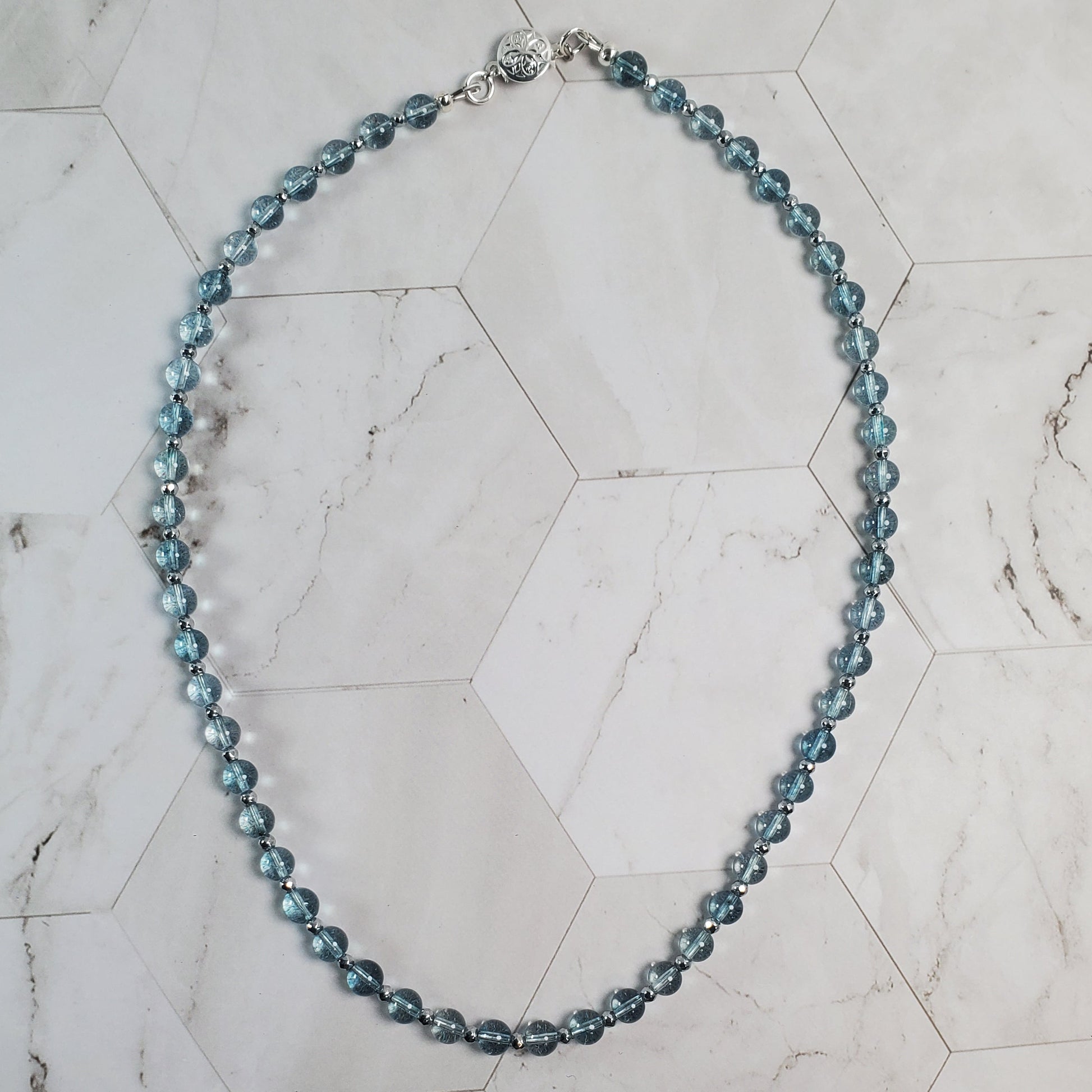 Blue beaded necklace on a marble surface