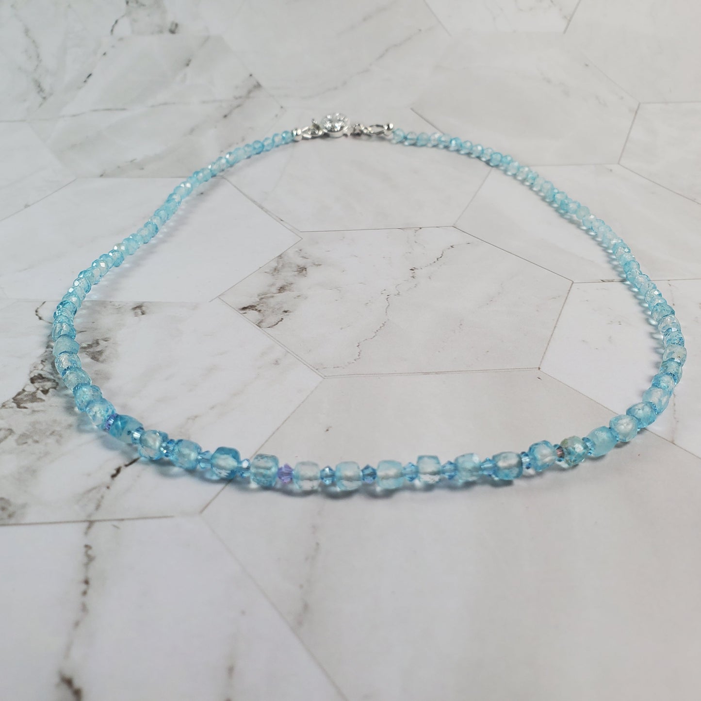 Blue beaded necklace on a marble surface