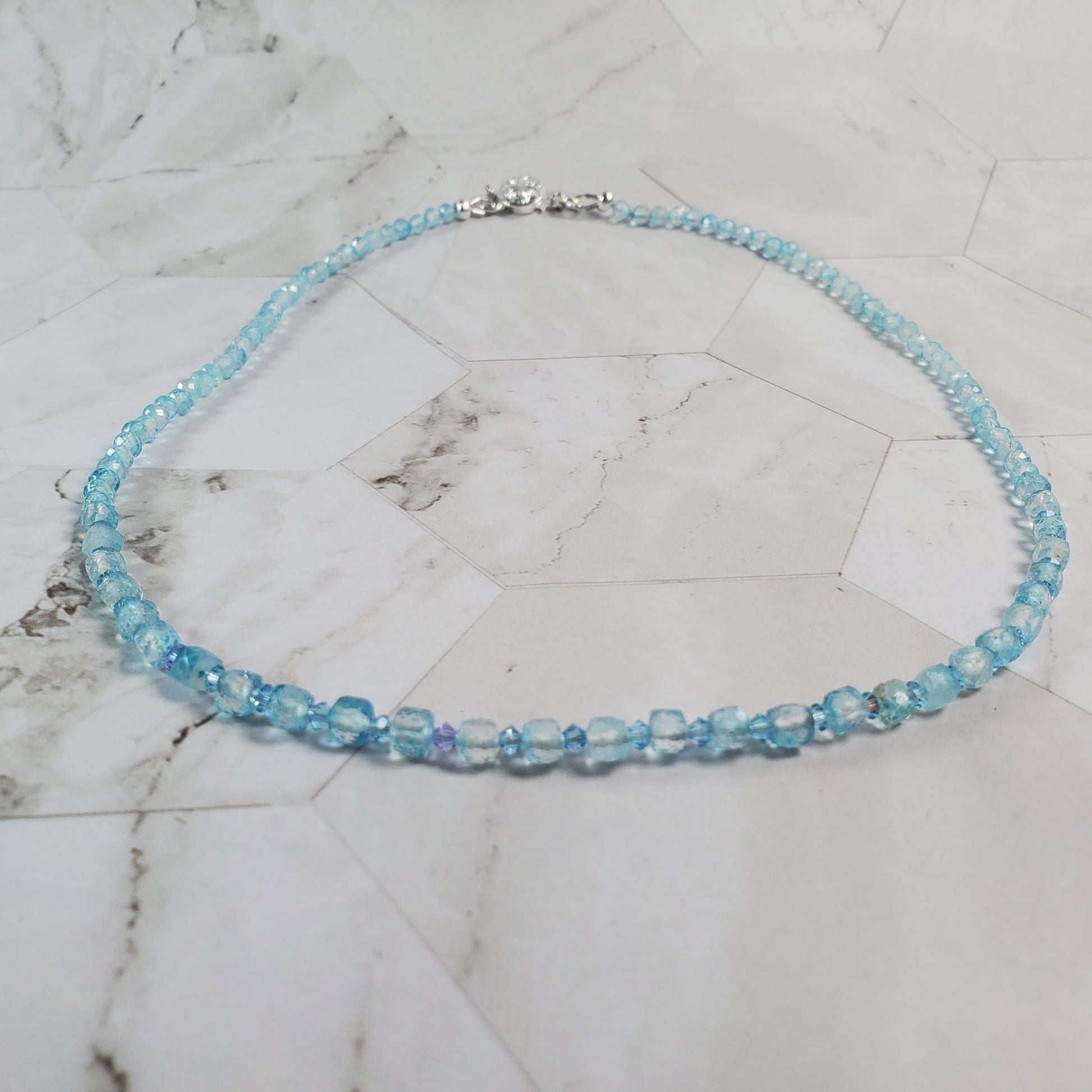 Blue beaded necklace on a marble surface