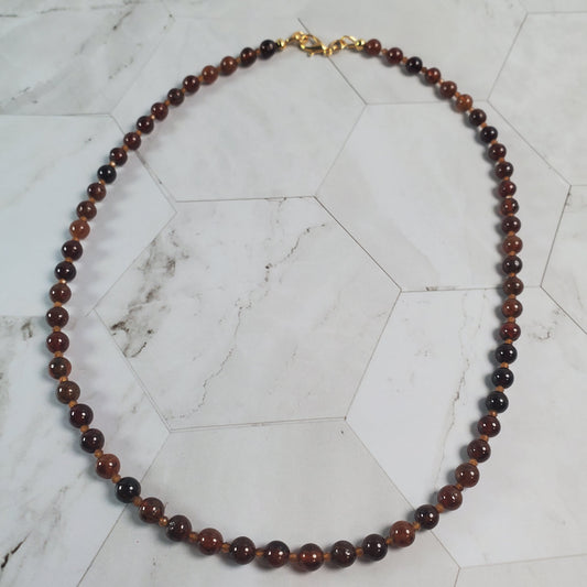 Necklace with brown beads on a marble surface