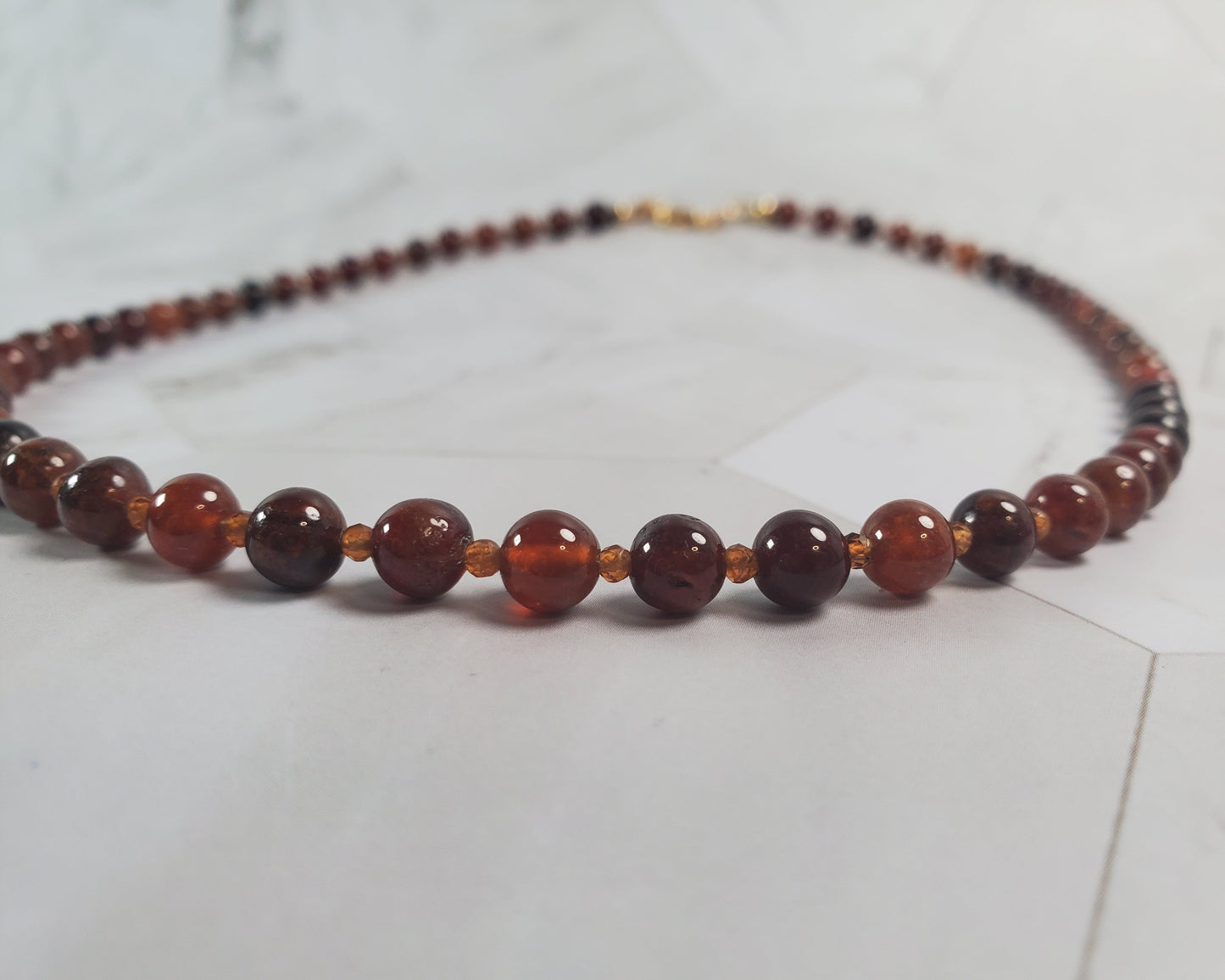 Beaded necklace with brown and red beads on a light gray surface