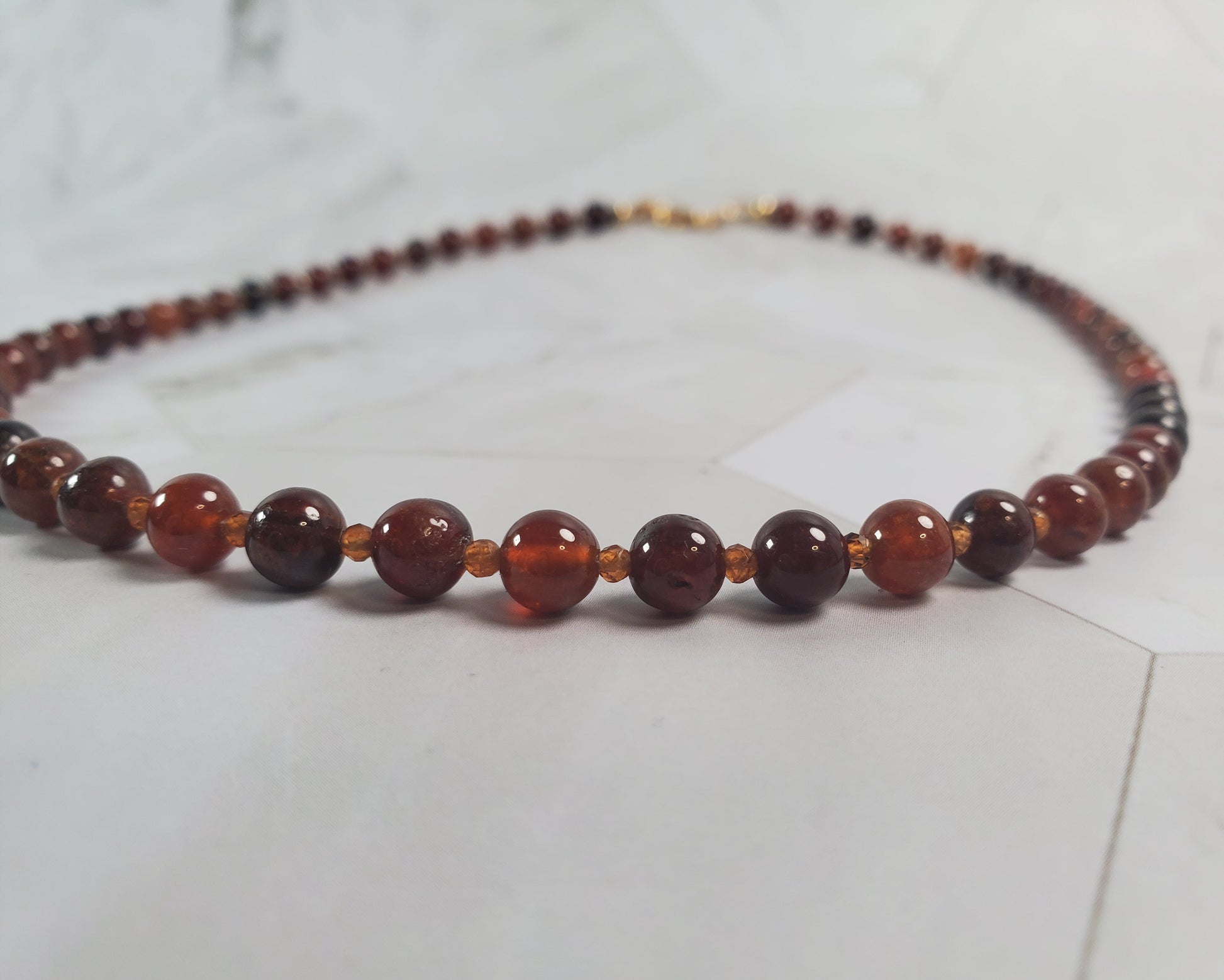 Beaded necklace with brown and red beads on a light gray surface
