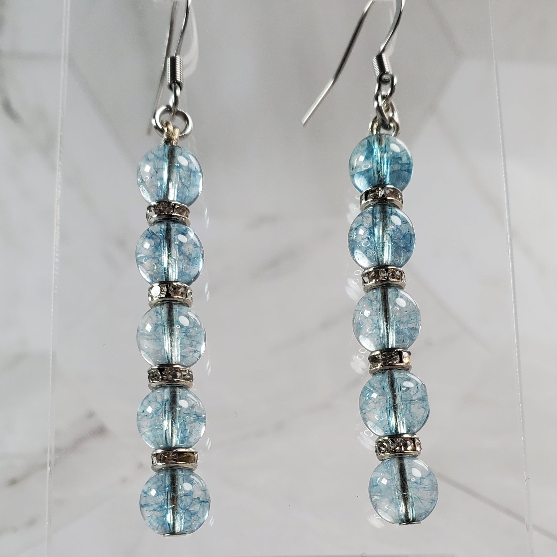 Pair of blue beaded earrings on a marble surface
