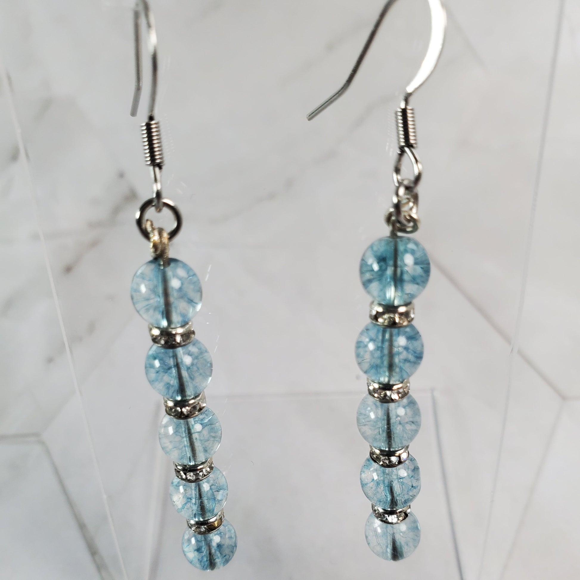 Pair of beaded earrings with light blue beads on a marble background