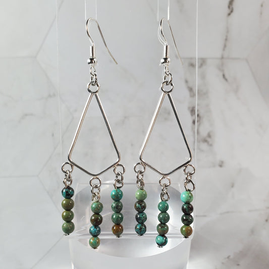 Beaded earrings on a white stand against a marble background