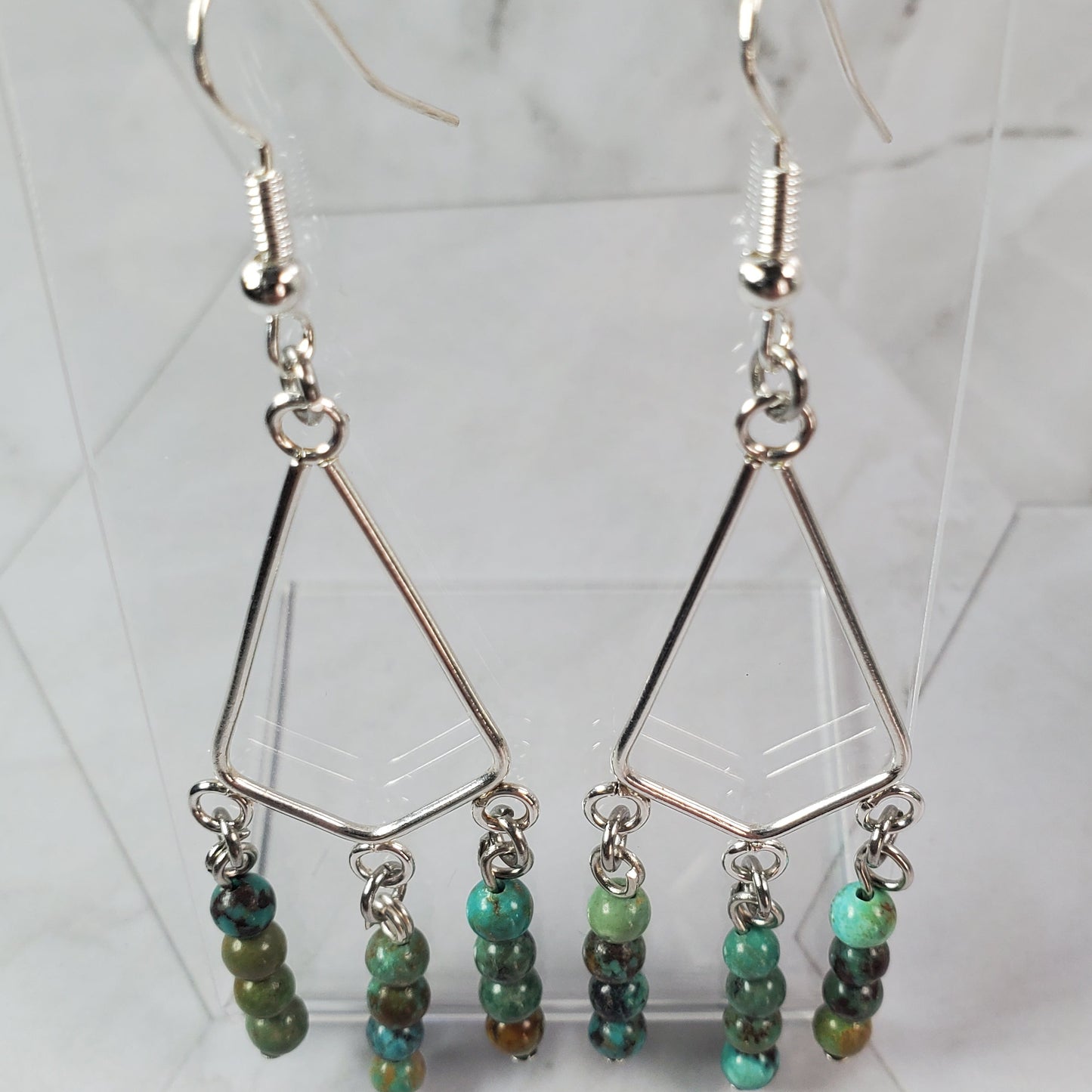 Pair of earrings with green beads on a marble surface