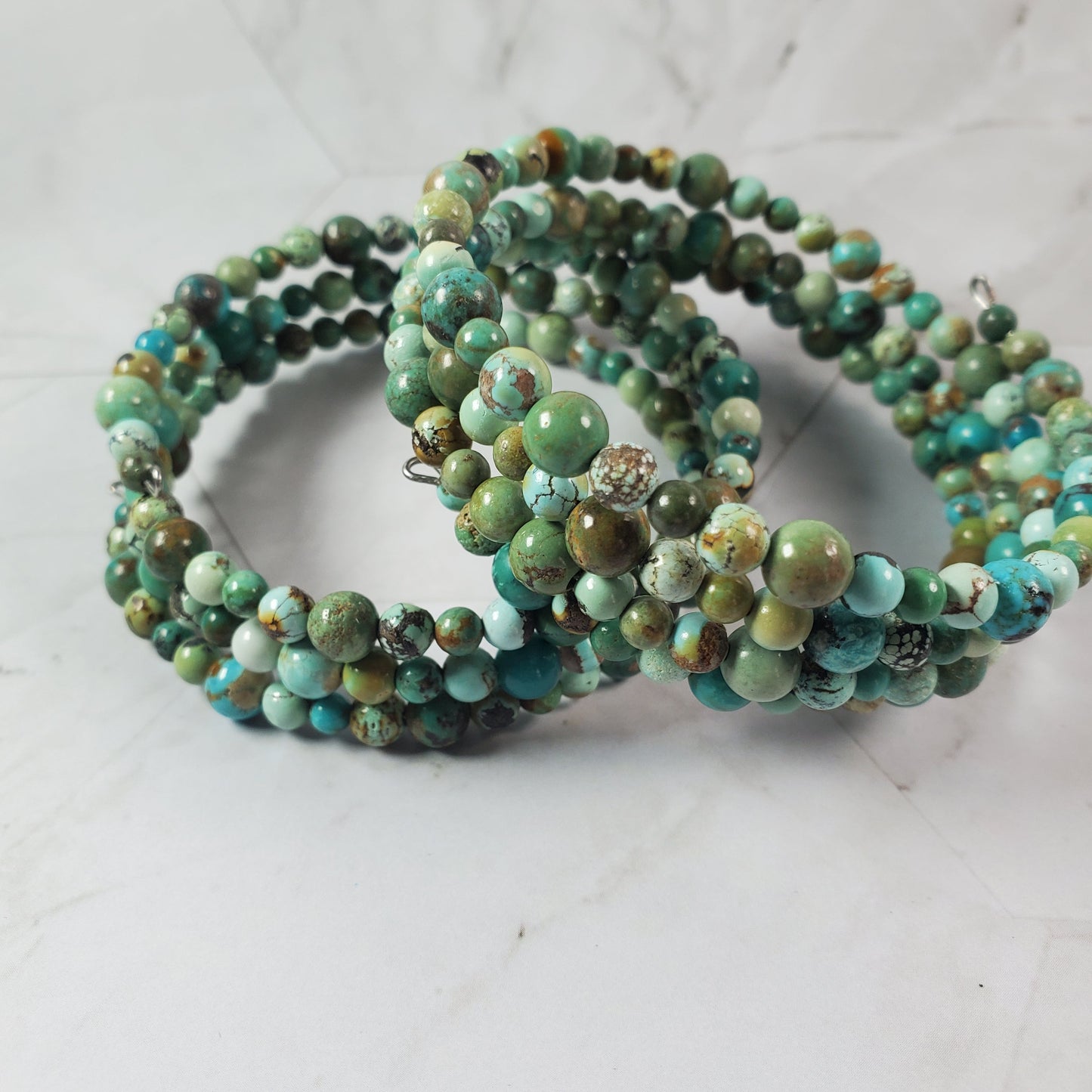 Stacked green beaded bracelets on a light gray background