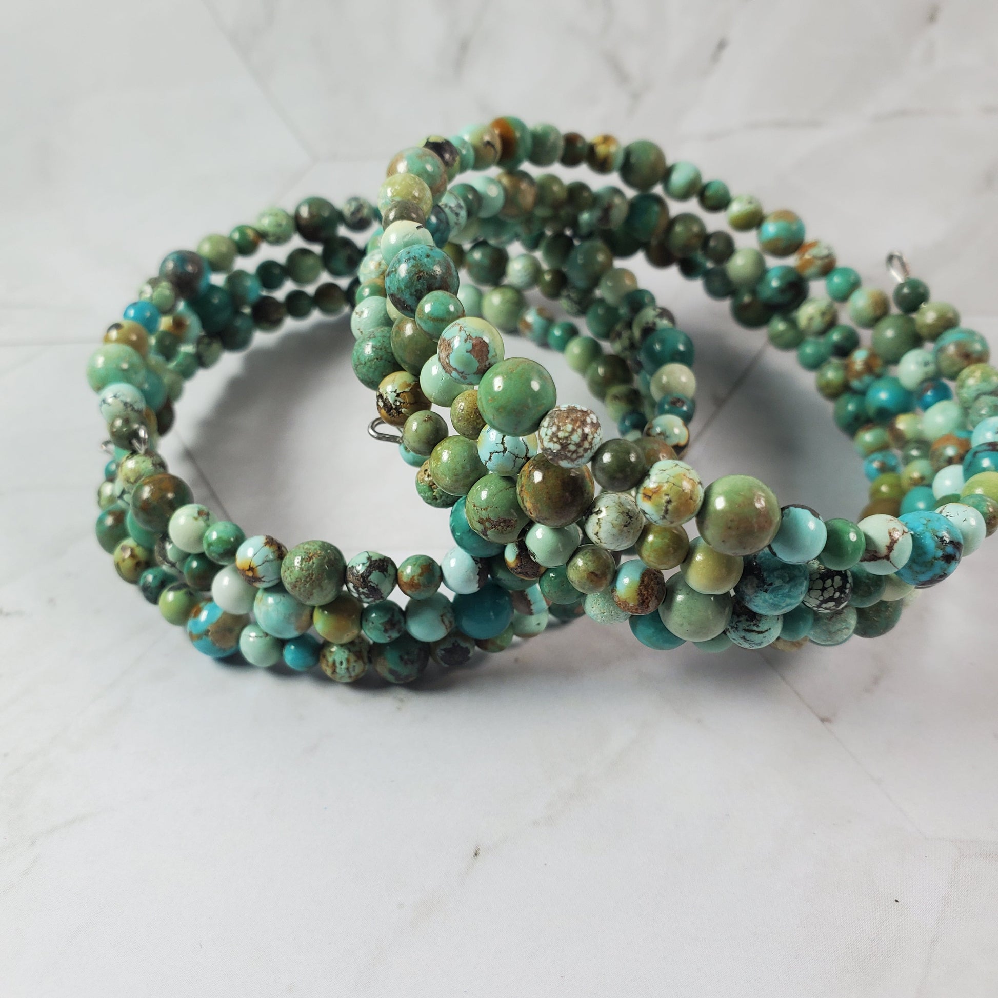 Stacked green beaded bracelets on a light gray background
