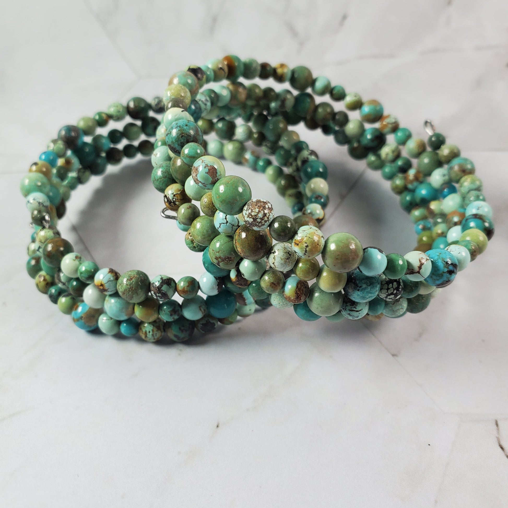 Set of green beaded bracelets on a light gray background