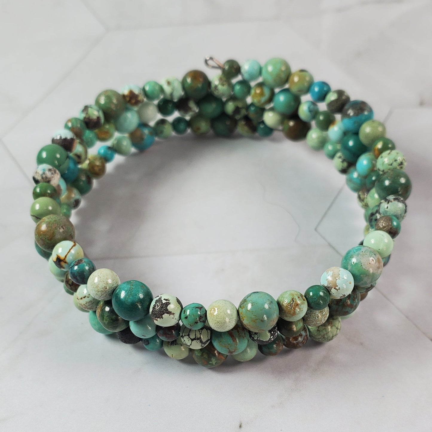 Green beaded bracelet on a light gray surface