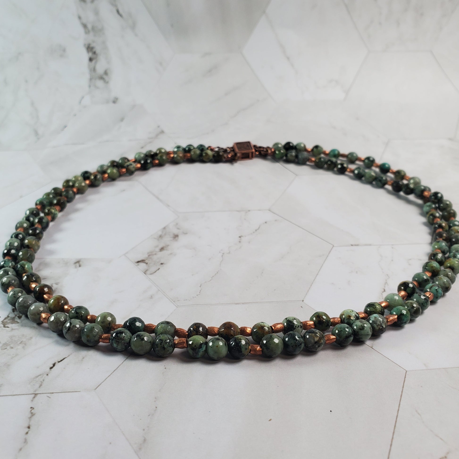 Necklace with green and brown beads on a marble surface