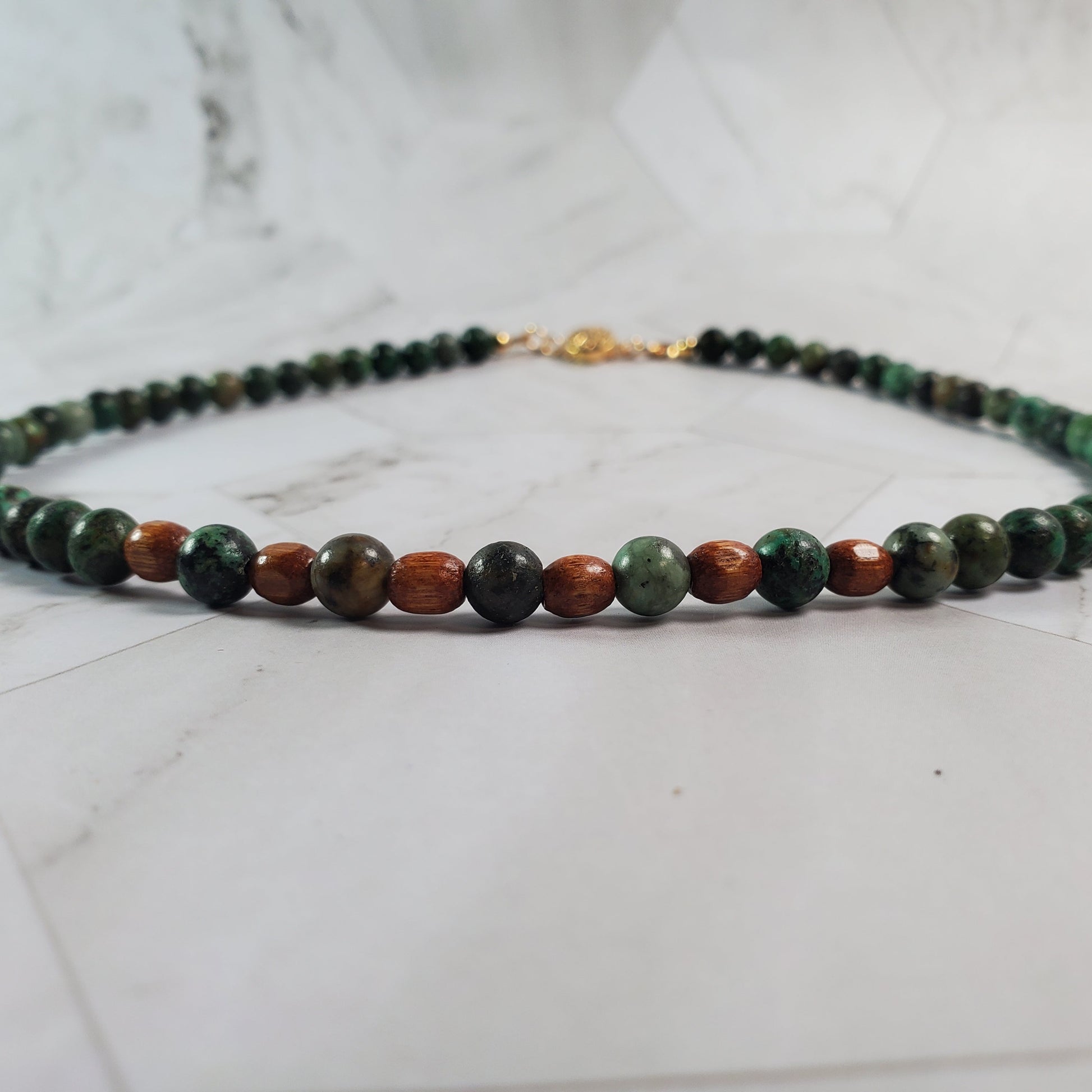 Necklace with green and brown beads on a marble surface