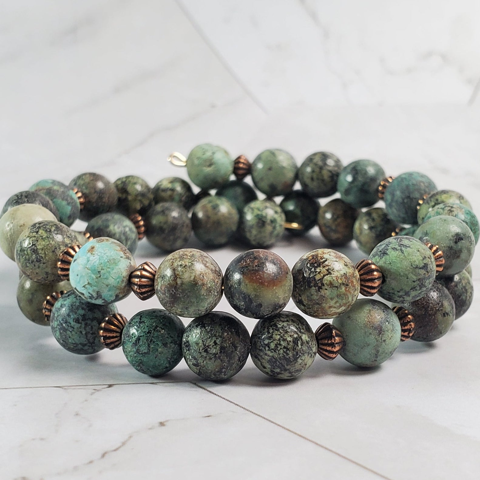 Green beaded bracelet on a marble surface