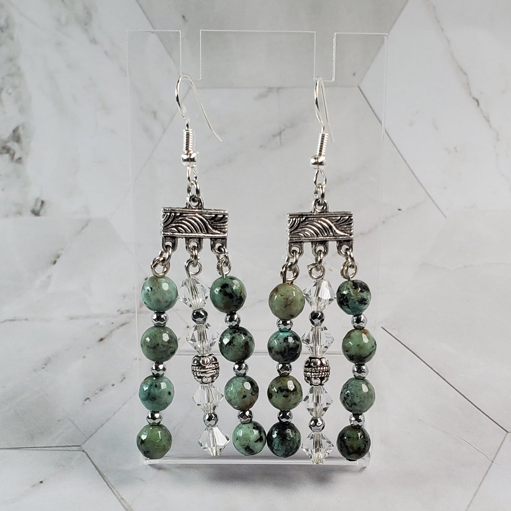 Decorative metal and green bead earrings on a marble surface