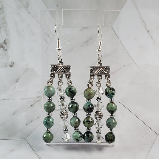 Decorative metal and green bead earrings on a marble surface