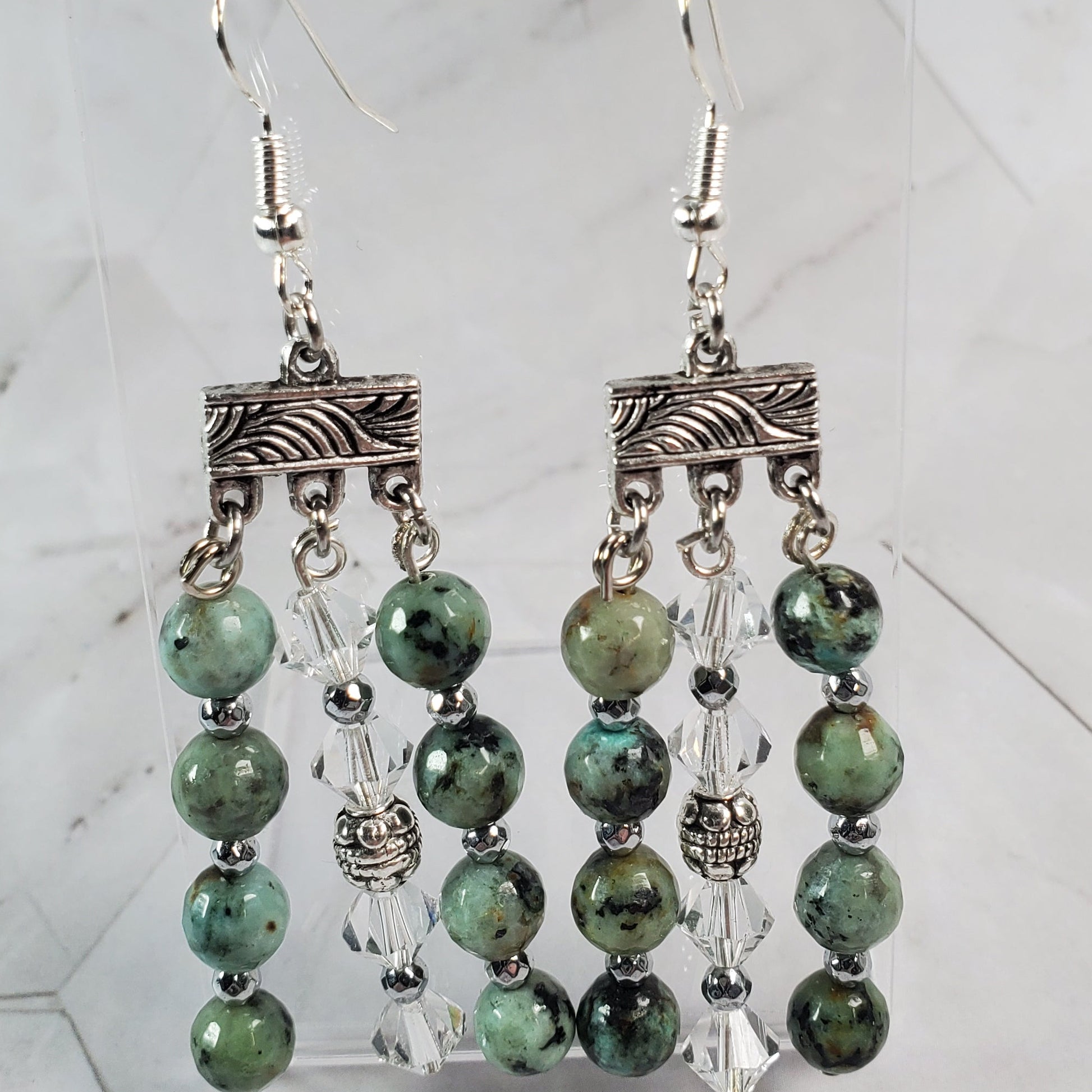 Pair of green beaded earrings on a marble surface