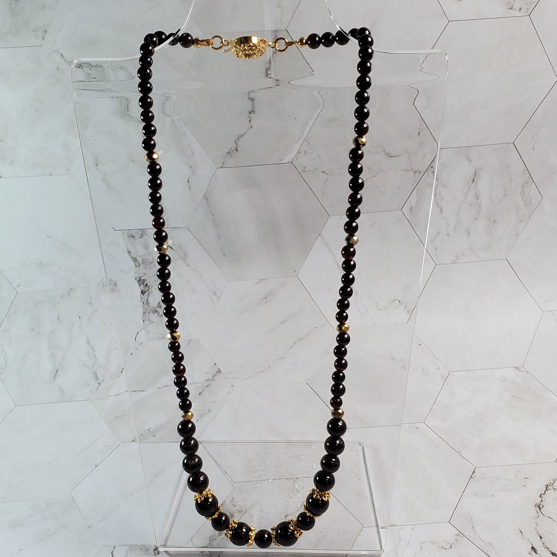 Necklace with Garnet beads and gold accents on a marble surface