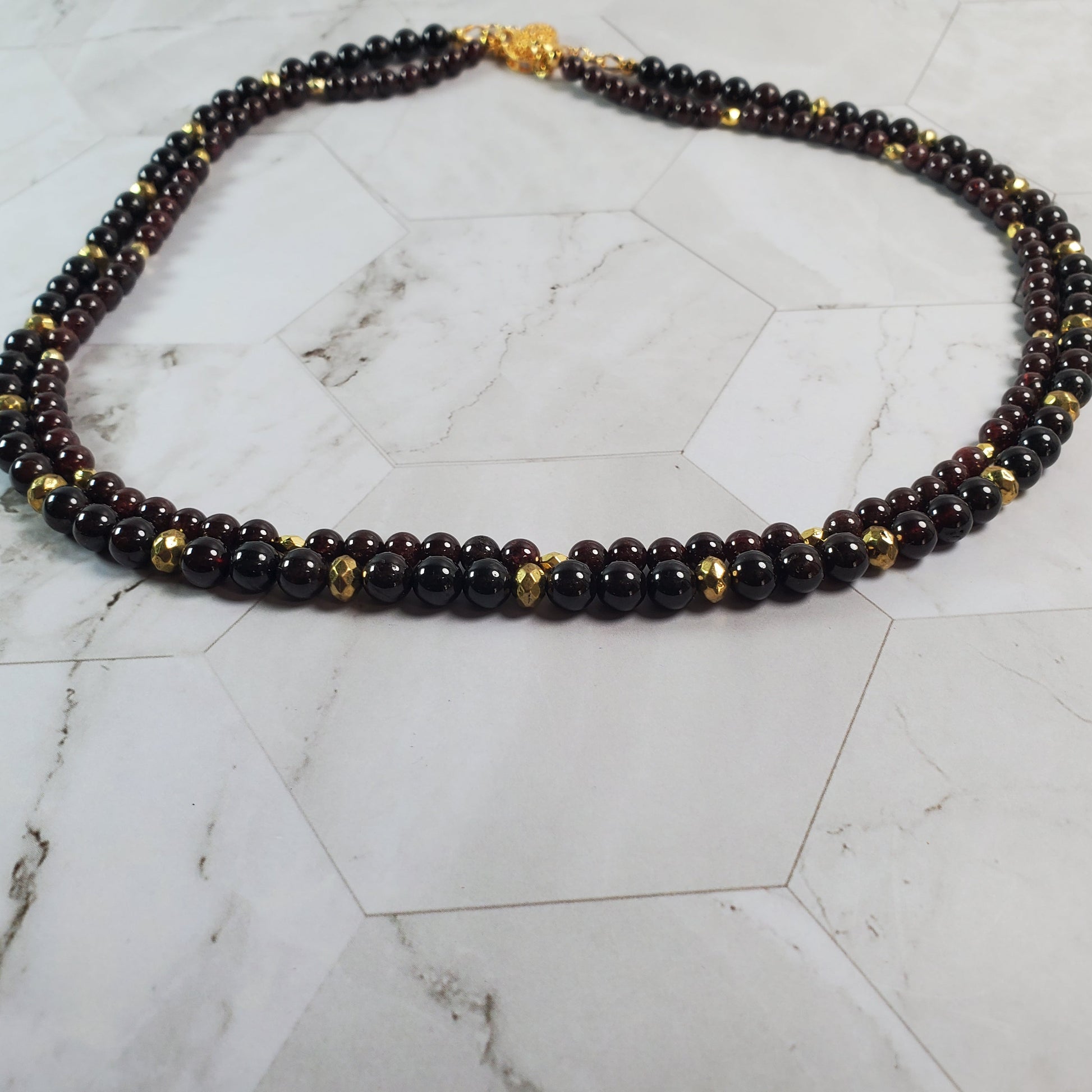 Beaded necklace with gold accents on a marble surface