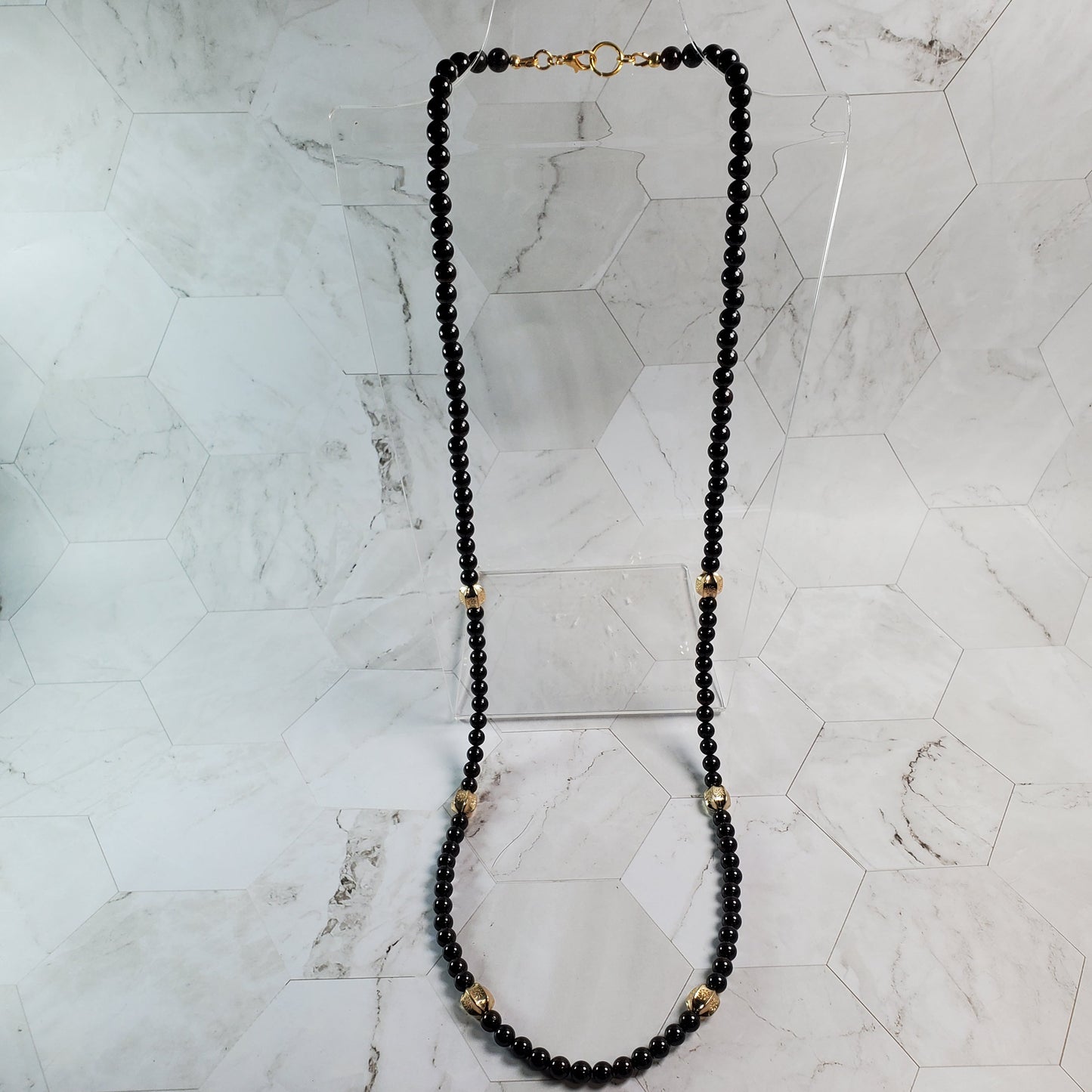 Garnet beaded necklace with gold accents on a marble surface