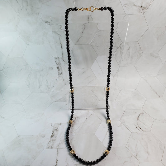 Garnet beaded necklace with gold accents on a marble surface