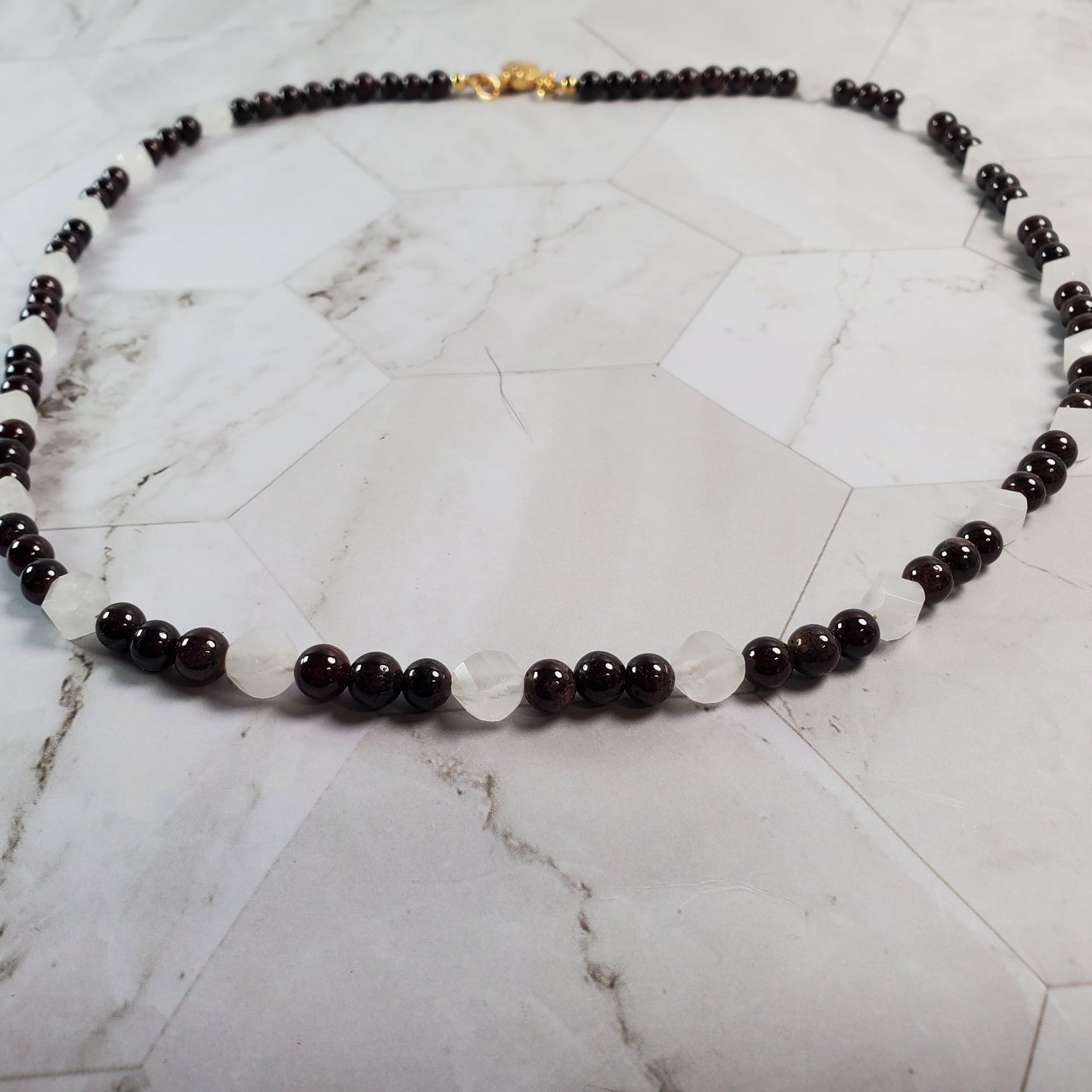 Necklace with dark beads on a marble surface