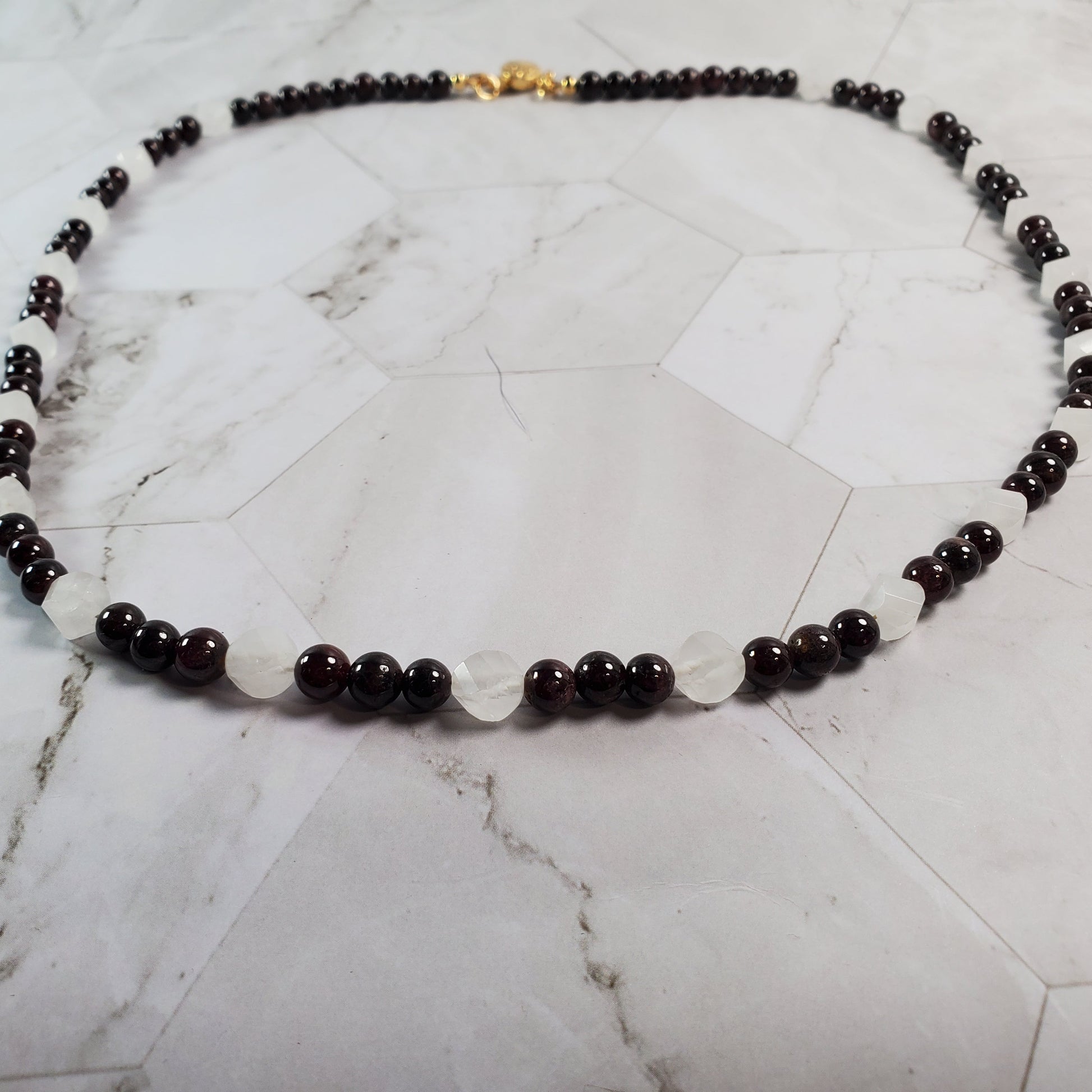 Necklace with dark beads on a marble surface