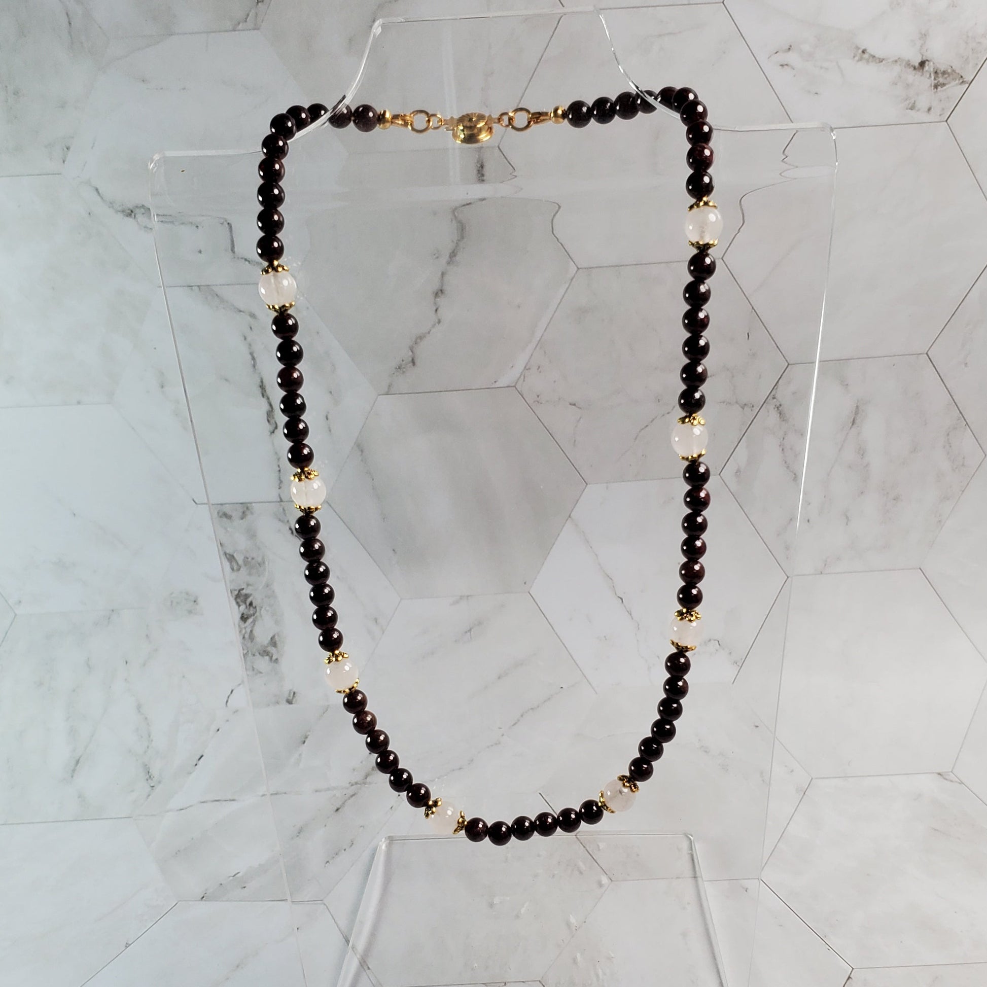 Necklace with Garnet and gold beads on a marble surface