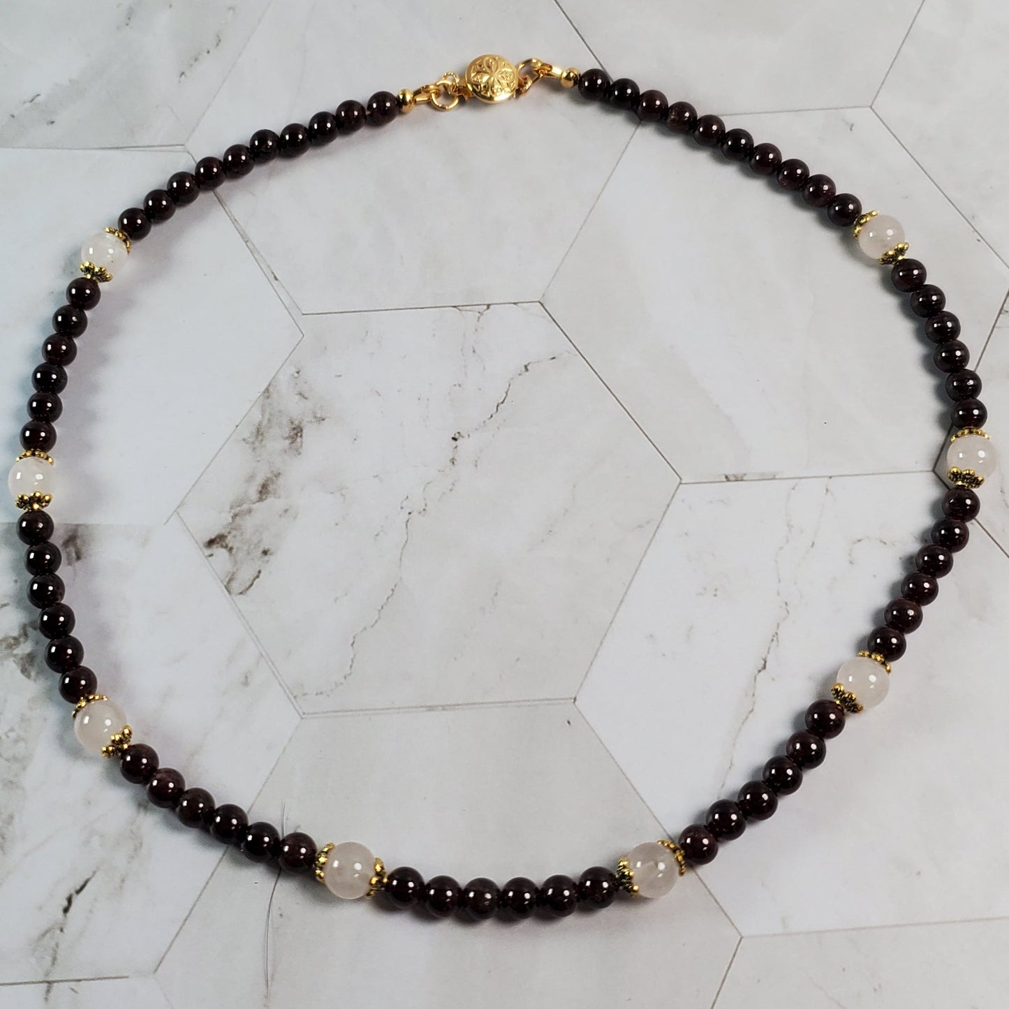 Necklace with Garnet and Pink beads on a marble surface