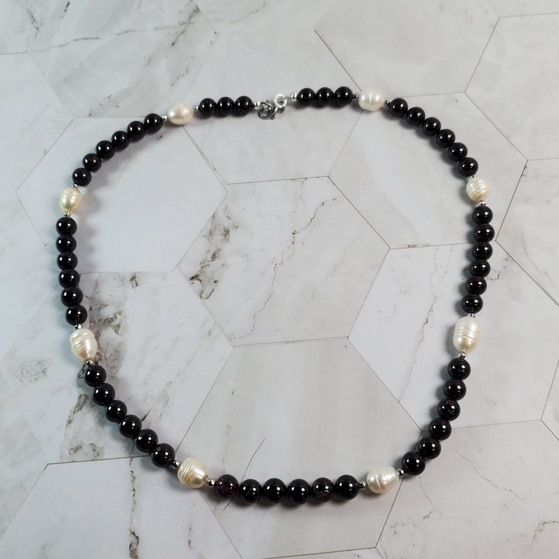 Necklace with deep red and white beads on a marble surface