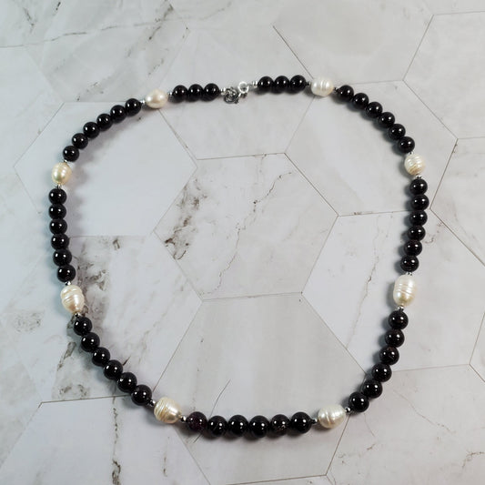 Necklace with deep red and white beads on a marble surface